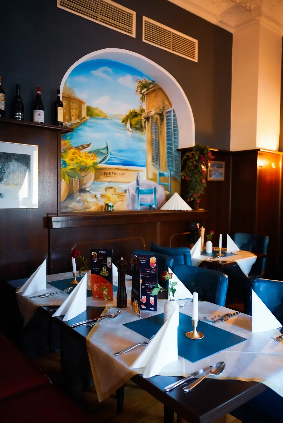 Gastraum des Portofino mit Riviera-Wandbild und gedeckten Tischen