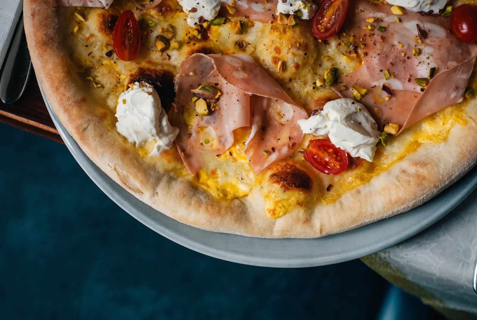 Pizza mit Parmaschinken und Burrata auf dem Tisch